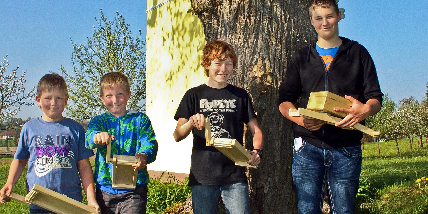 Vier Kinder vor einer kleinen Kapelle im herrlichen Sonnenschein mit ihren Ratschen